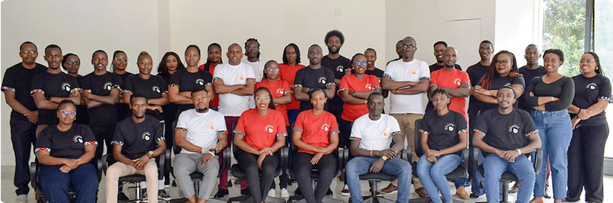 A group of BrighterMonday employees sitting and standing together in two rows, wearing a mix of red, black, and white branded t-shirts, posing inside a room. Above them, text reads: 'Discover Your Future with BrighterMonday. Be a part of the BrighterMonday Crew.' with a button below that says 'Explore careers.'